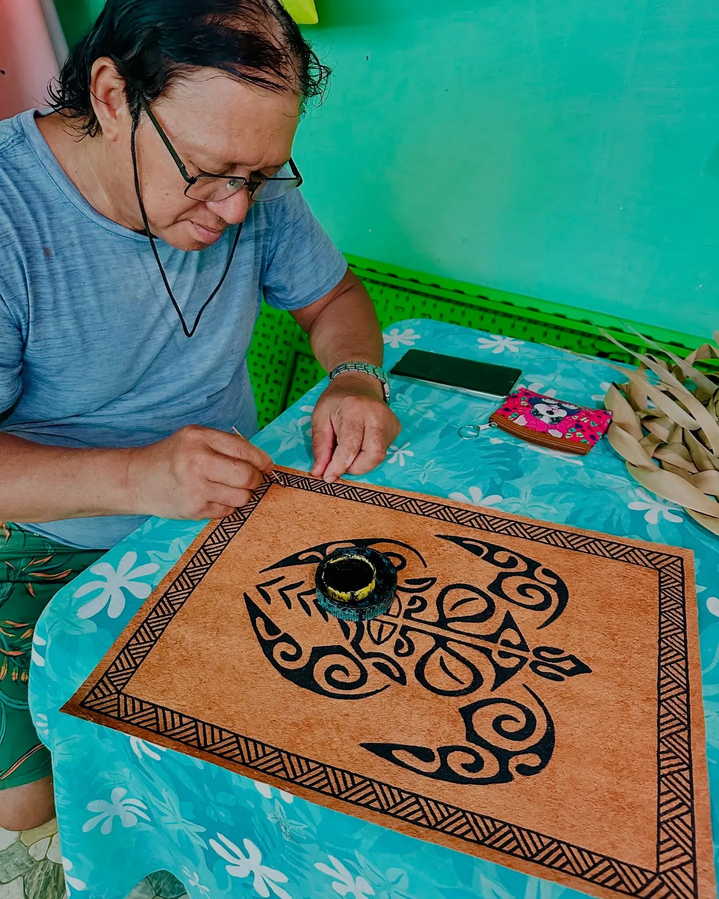 Painting a design onto the bark cloth. Painting a design onto the bark cloth.