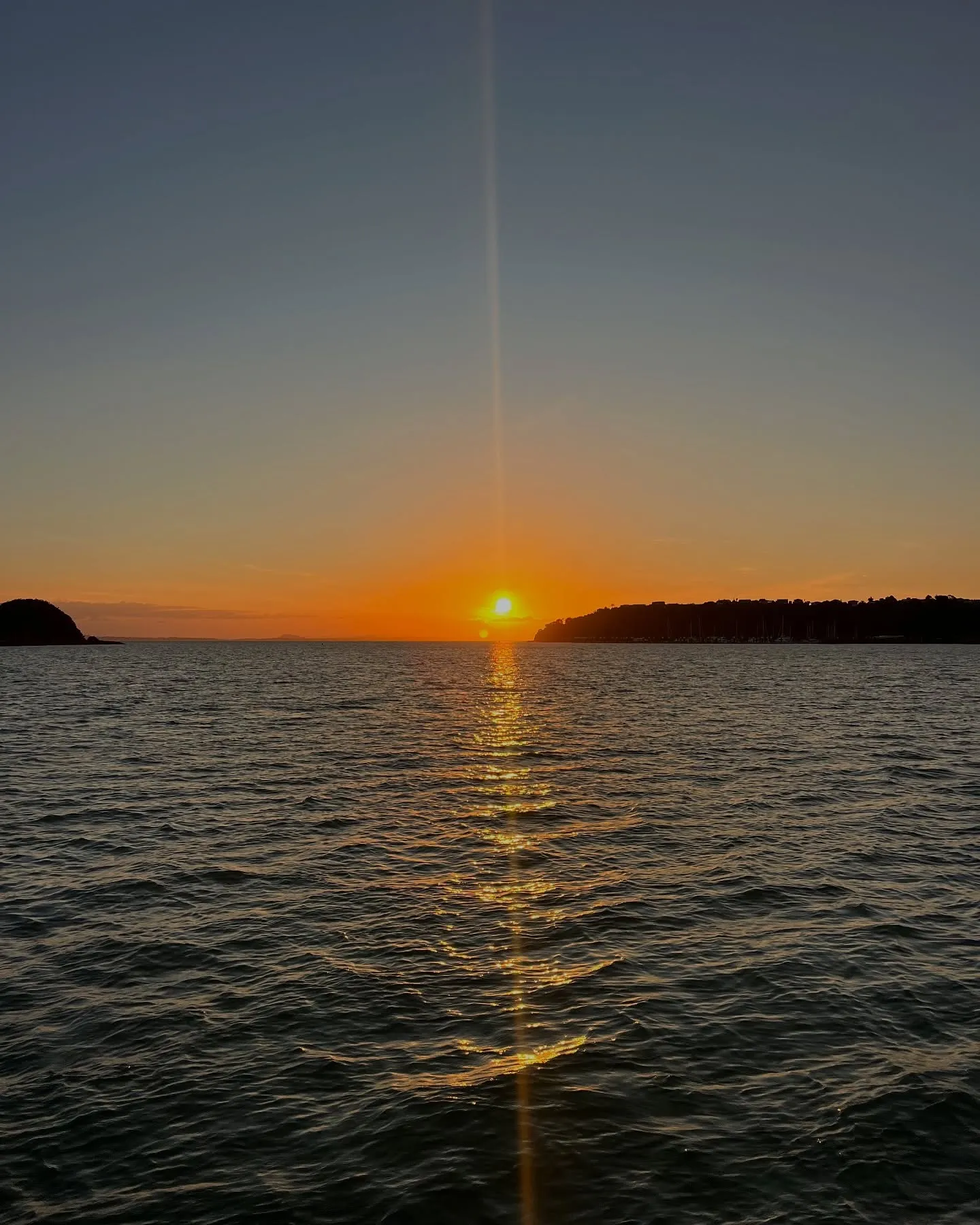 The sun sinks between the headlands. The sun sinks between the headlands.