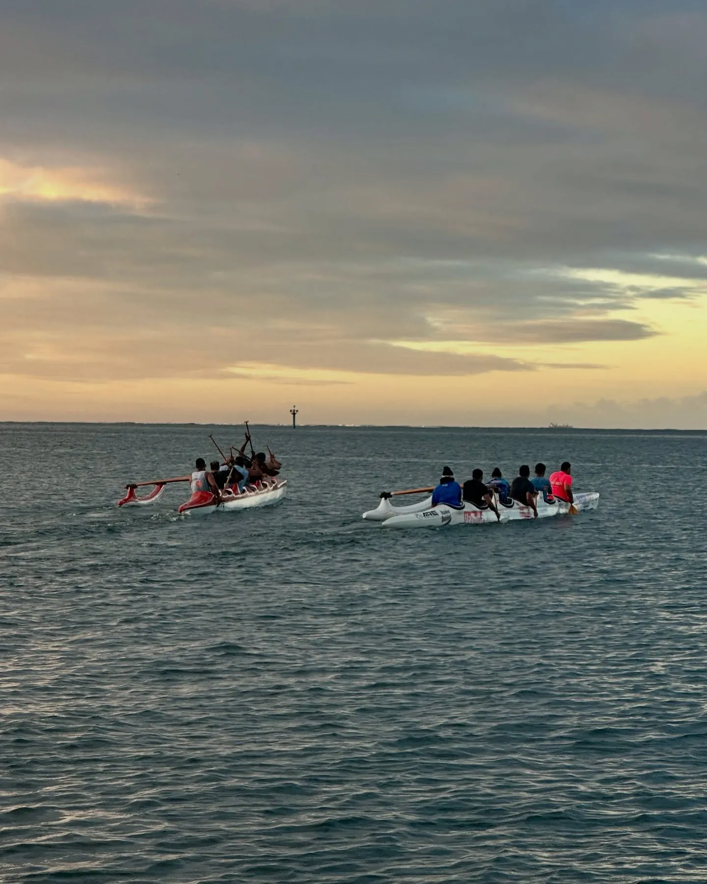 Outrigger canoes paddling out at dusk.